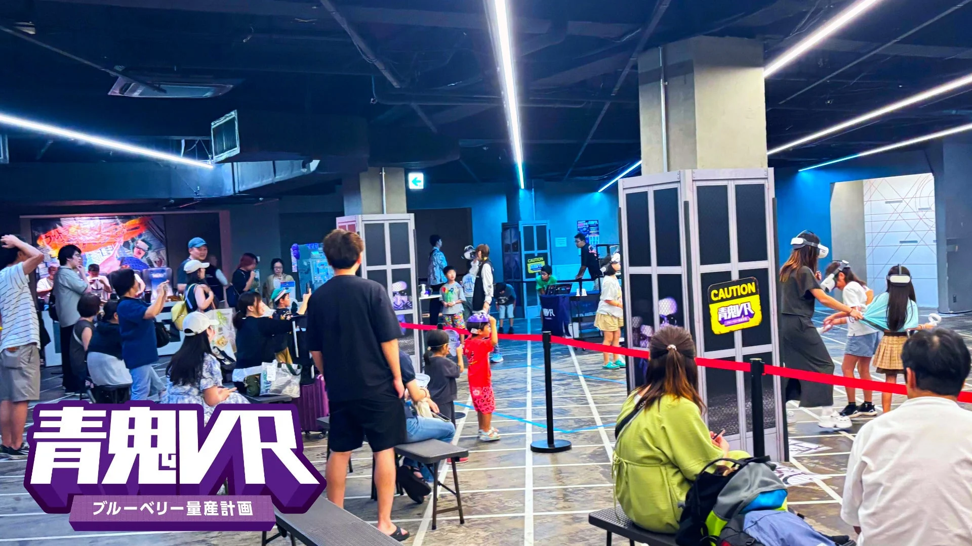 多くの人々がVRヘッドセットを装着してバーチャルリアリティ体験を楽しんでいる屋内のイベント会場の様子です。青鬼VRのロゴや看板が見られ、VRゲームイベントの賑わいが伝わってきます。