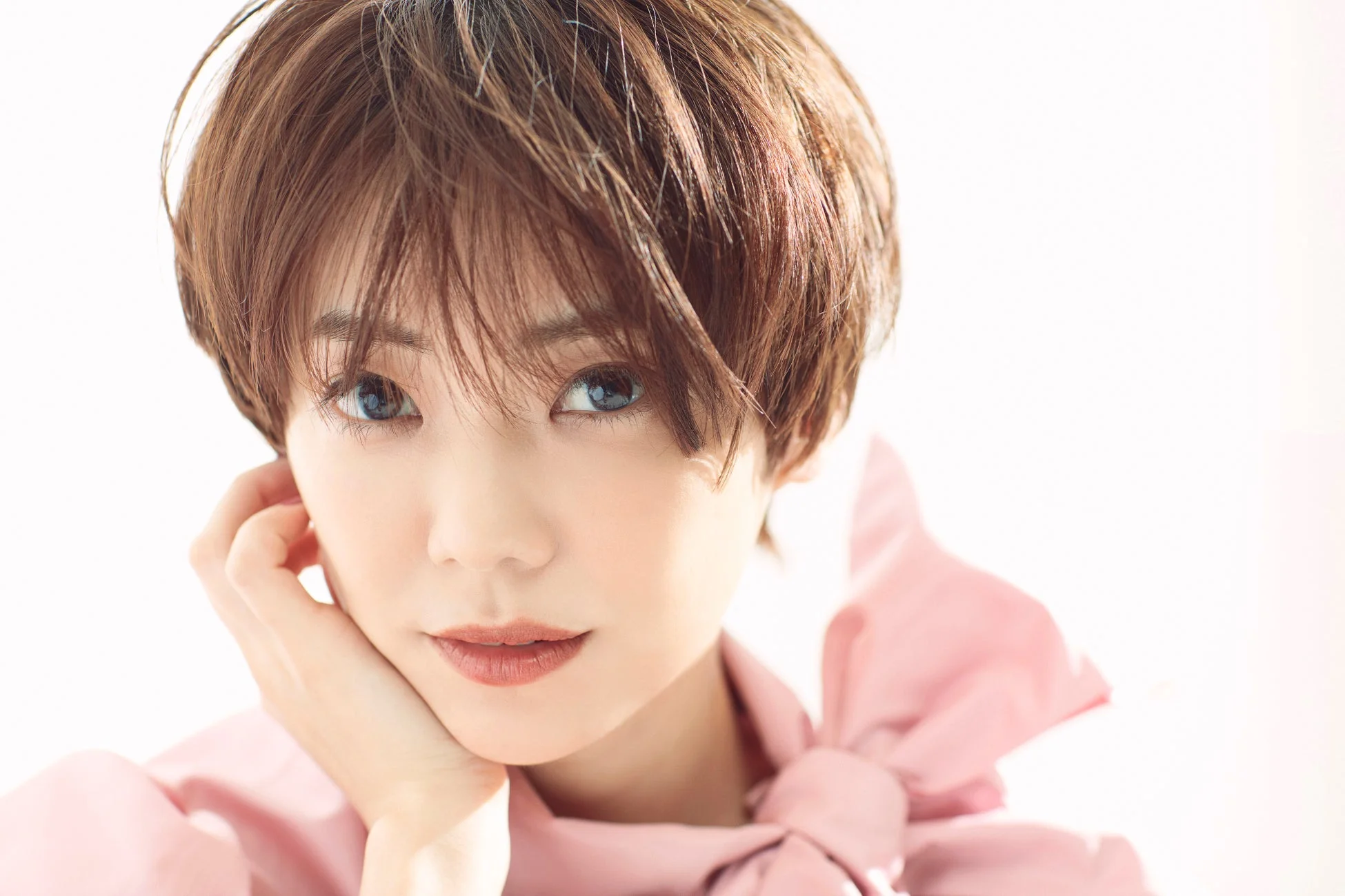 ショートヘアの女性が顎に手を当ててカメラを見つめているポートレート