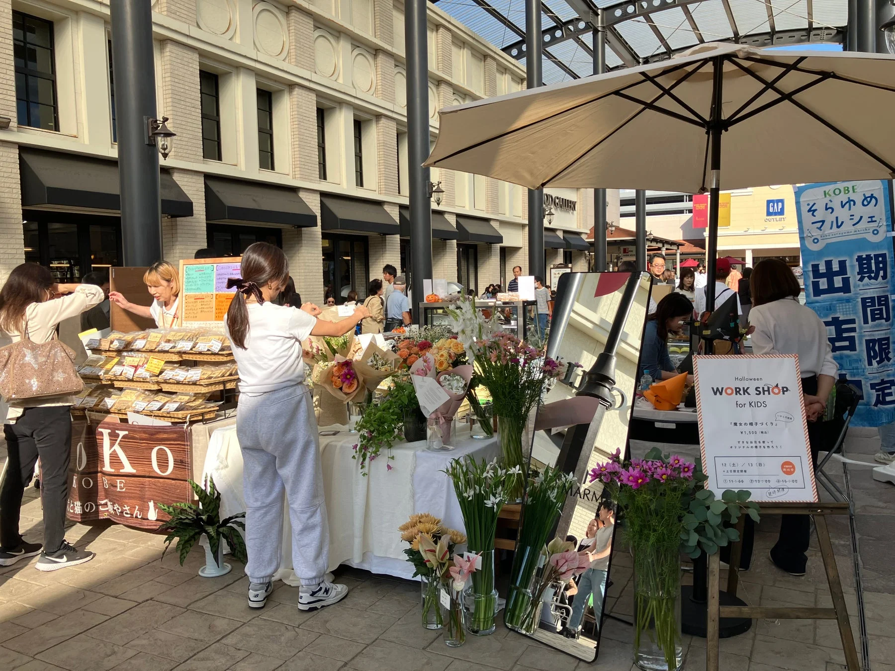 屋外マルシェの様子、花や焼き菓子などの店が並ぶ